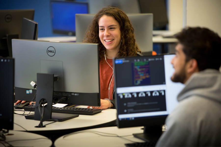 Two students work on PC computers to determine network architecture.