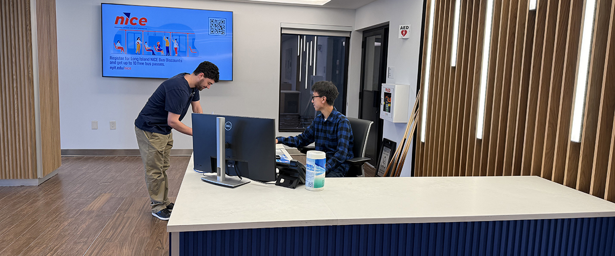 A student checks in at the front desk of the Long Island Residence Hall.