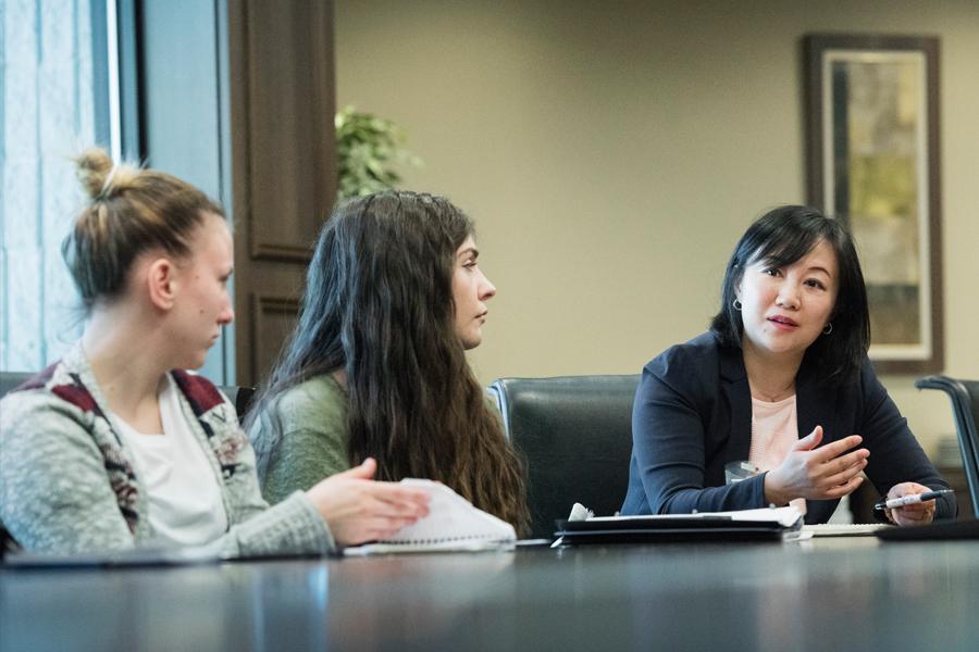 Three people sitting in a conference room at a large table.