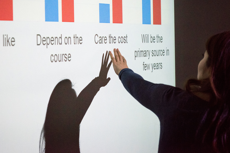 An instructor presenting graphs projected on a wall in classroom.