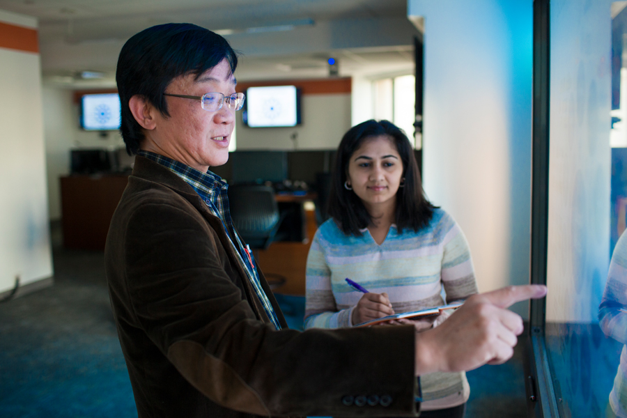 Two people working on a large touch screen. 