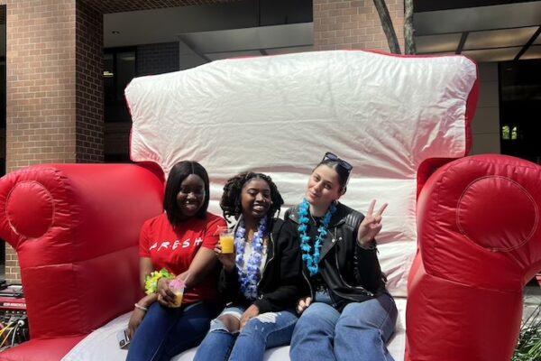 Three students on a giant chair prop posing