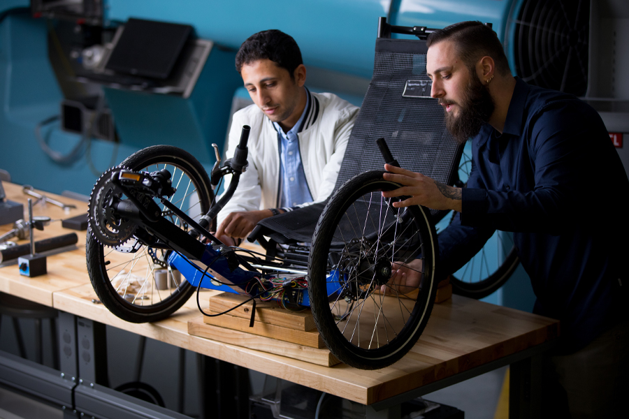 For one of New York Tech's accelerated dual degree pathways, a Mechanical Engineering, B.S. student studies movement and gravity with a faculty member while using a bicycle gyroscope.