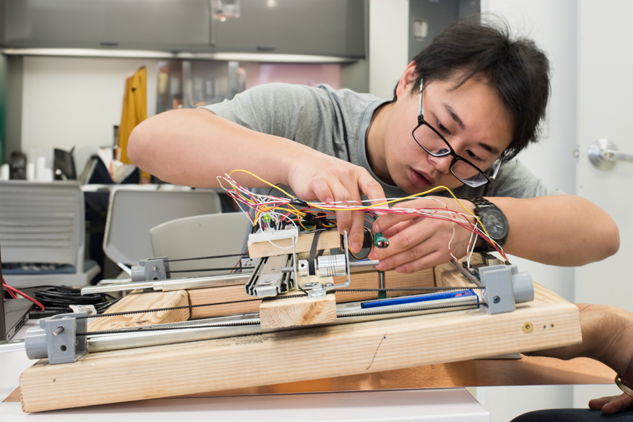 A New York Tech Mechanical Engineering, B.S. student connects wires and other components to complete a project.