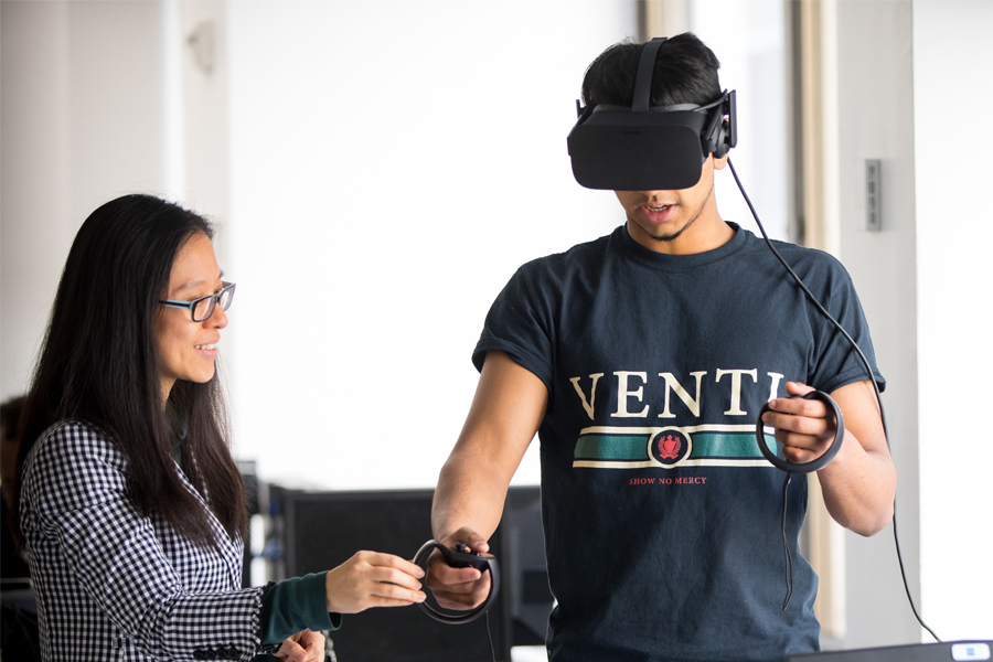 Two students pictured one with a VR headset and other assisting.