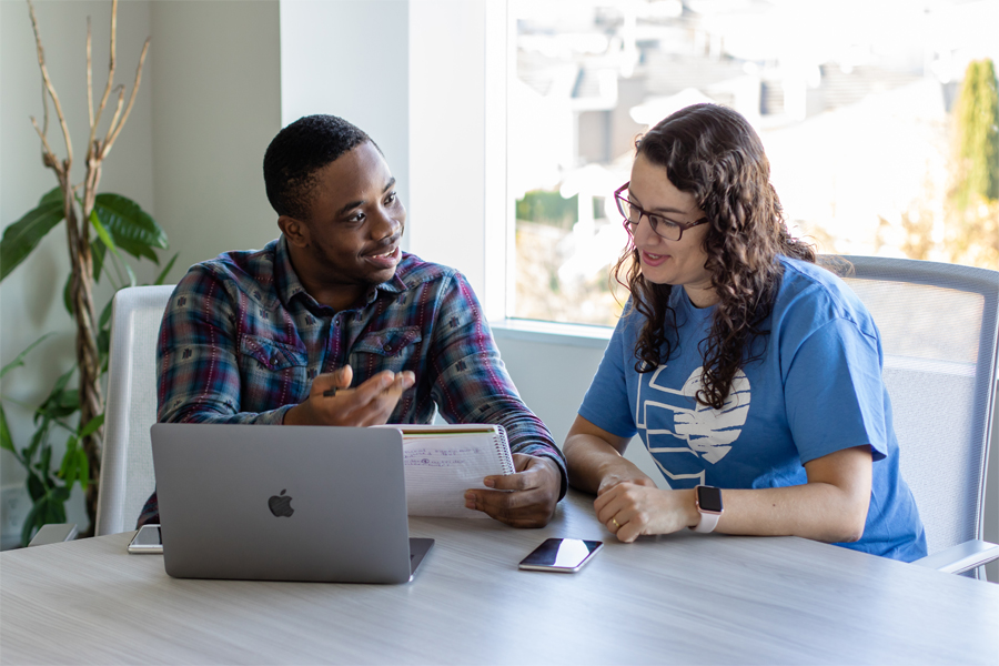 Two students studying at a large table with a laptop in front of them.