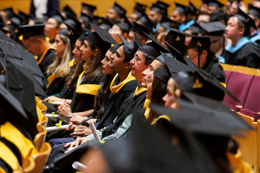 Group of graduates wearing caps and gowns sitting in an auditorium