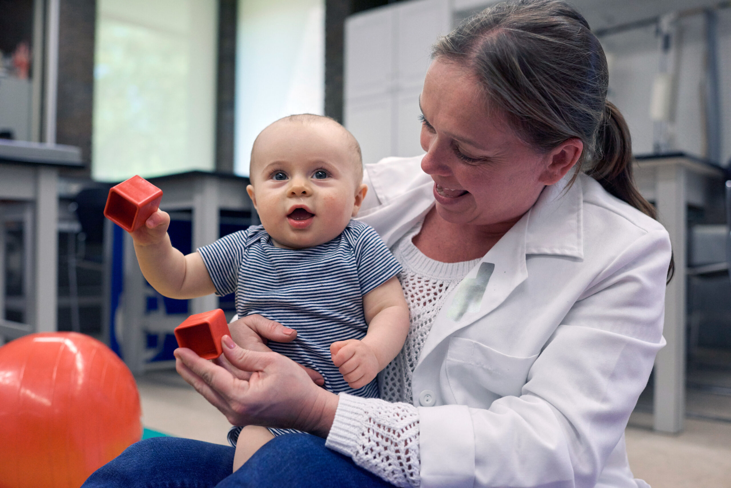 A person is a white coat is holding a baby. 