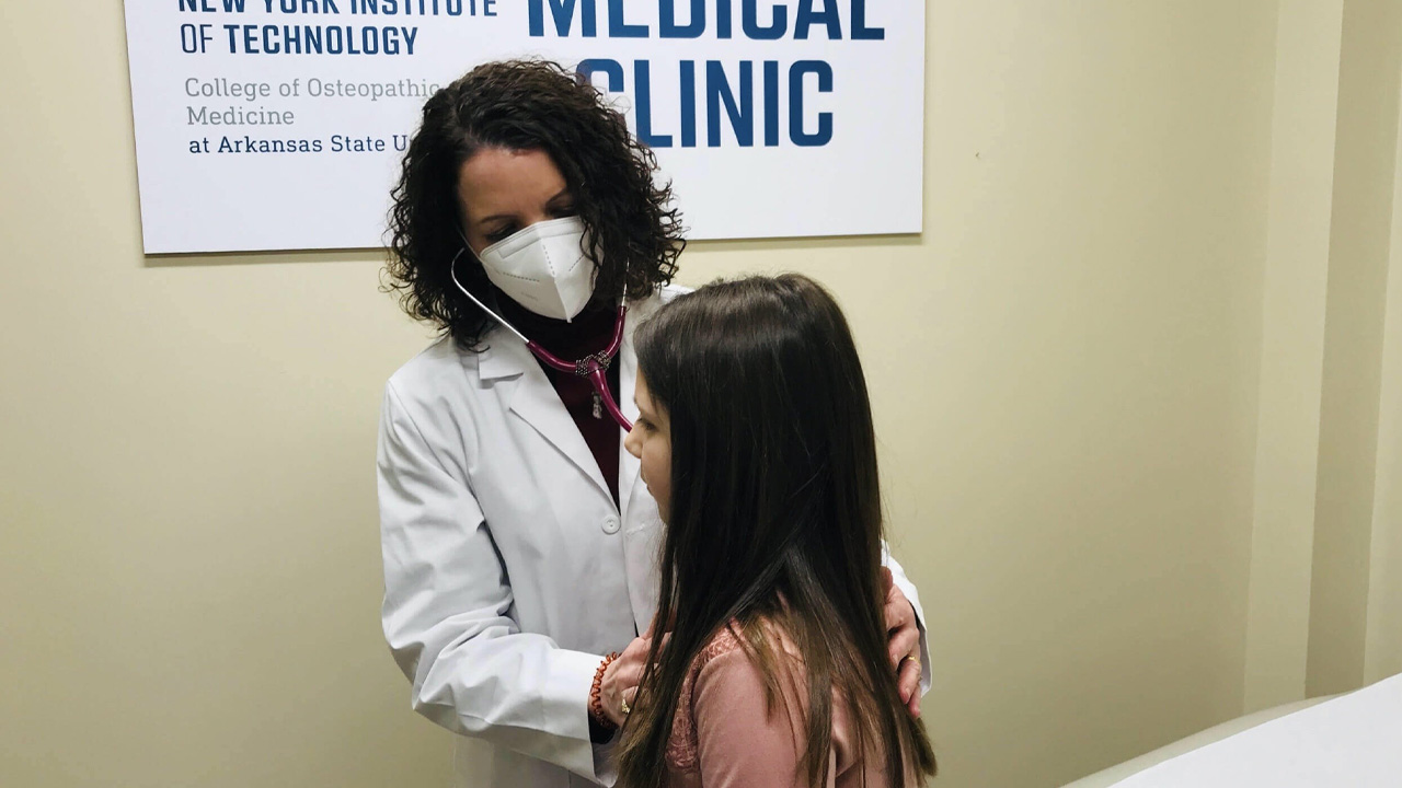 Doctor wearing a mask checking a young patient.