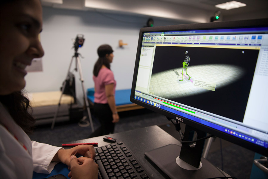 Two students work together. One is wearing tracking equipment and the other is monitoring her movements on a computer screen.