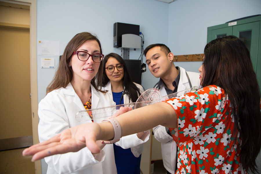 A medical school professor working with two medical students and a patient in a clinic. 