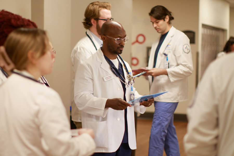 A group of medical students looking over charts in a hallway.