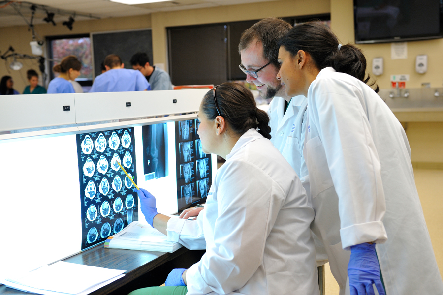 A group of three medical students review medical images.