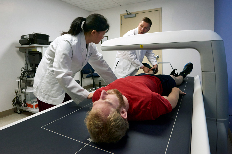 Two medical students setting a patient up on a scanning device. 