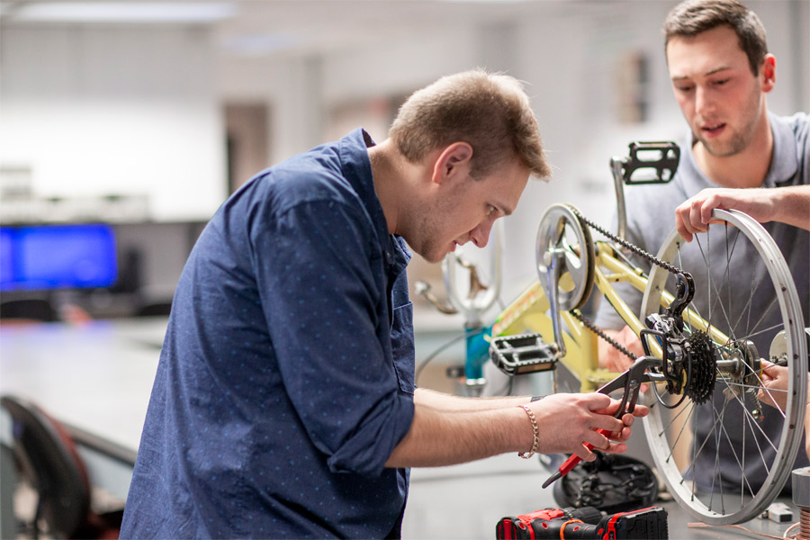 Two people work on a bicycle in a lab.