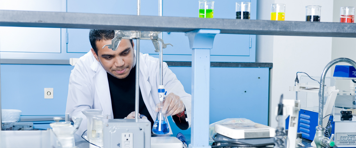 A man looking at a beaker in a lab