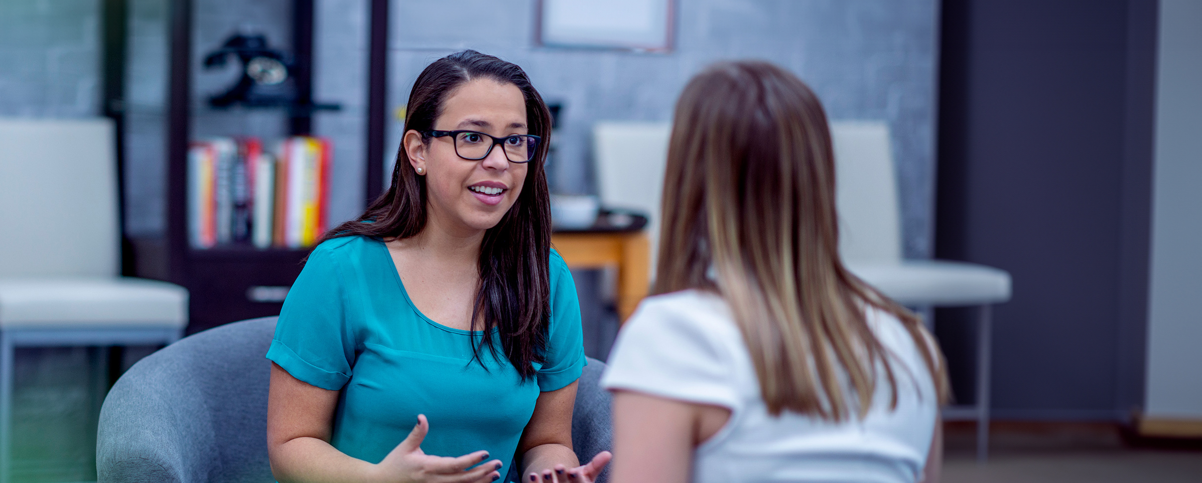 A faculty member from New York Tech's Department of Psychology and Counseling has a conversation with a student in a common area.