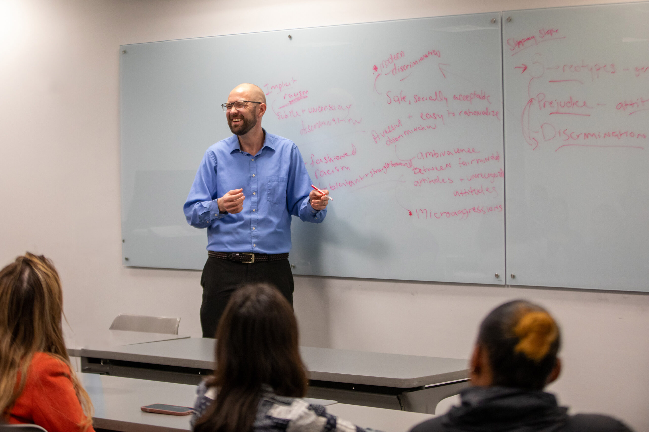 A professor stands in front of a whiteboard with red writing in a class for one of the Department of Psychology and Counseling's undergraduate programs at New York Tech.